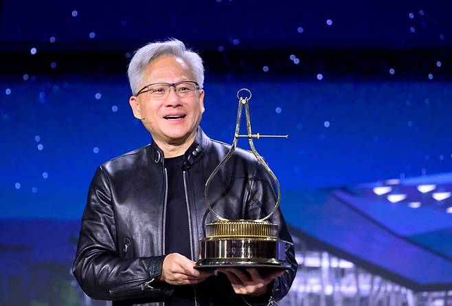 젠슨 황 엔비디아 최고경영자(CEO)가 17일(현지시간) 캘리포니아주 산호세에서 열린 엔비디아 연례 GTC 개발자 컨퍼런스 질의응답 시간에 ‘2026 모터트렌드 올해의 인물’ 트로피를 수상받는 모습. [AFP]