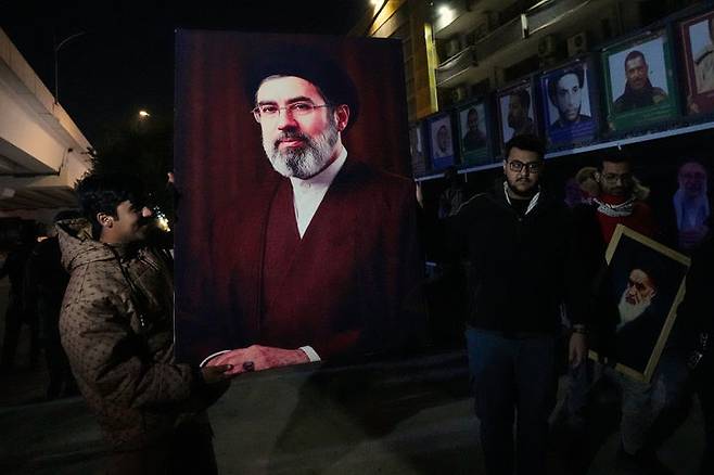 [바그다드=AP/뉴시스] 9일(현지 시간) 이라크 바그다드에서 이라크인들이 이란 최고지도자로 선출된 모즈타바 하메네이를 지지하는 의미로 그의 초상화를 들고 있다. 모즈타바 하메네이는 미·이스라엘의 공습으로 사망한 아야톨라 알리 하메네이 전 최고지도자의 차남으로 8일 이란 최고지도자로 선출됐다. 2026.03.10.