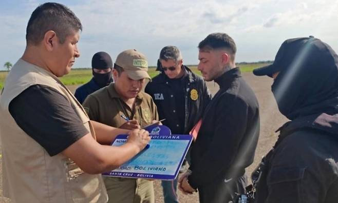 볼리비아 경찰이 검거한 마약두목 마르셋(가운데 검은 옷을 입은 남성)이 신병을 미국에 넘기고 있다. 에페 캡처