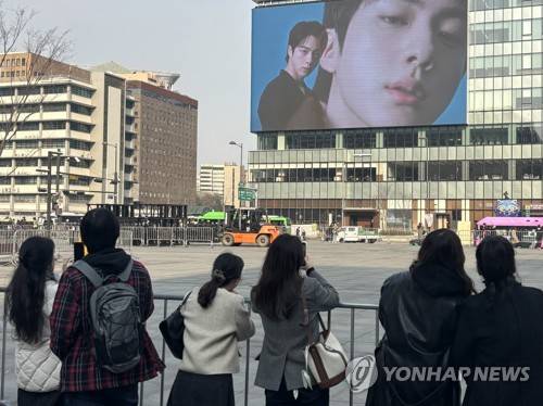 "방탄소년단(BTS)이다!" (서울=연합뉴스) 이진주 인턴기자 = 지난 16일 광화문 세종문화회관 'BTS 계단' 앞에서 맞은편 전광판에 나오는 BTS 광고를 보고 있는 외국인들. 2026.3.18