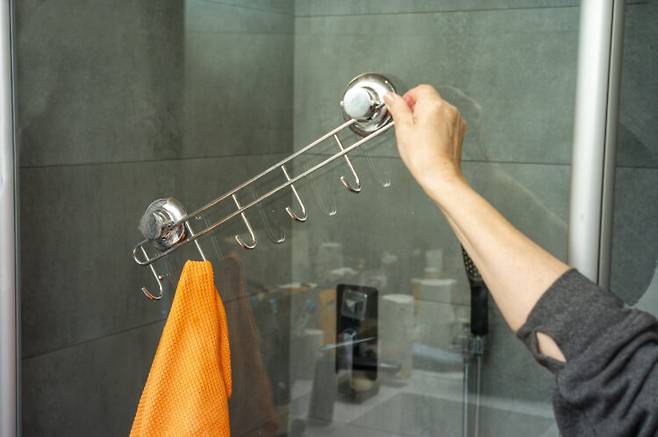 a hand holding damaged bathroom suction towel hooks, indoor close up