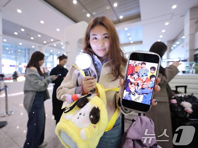 19일 인천국제공항에서 BTS 팬클럽 ‘아미’인 중국인 클로이(20)가 입국하며 아미밤(방탄소년단 공식 응원봉)과 멤버들의 사진을 들어 보이고 있다. 2026.3.19 ⓒ 뉴스1 박지혜 기자