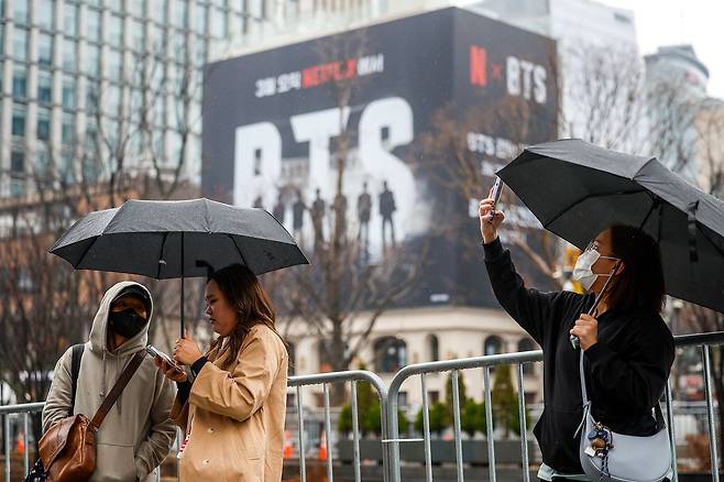방탄소년단(BTS)의 서울 광화문광장 컴백 공연을 앞둔 18일 서울 종로구 광화문광장을 찾은 외국인 팬들이 BTS 랩핑 앞에서 사진을 찍고 있다. [뉴시스]
