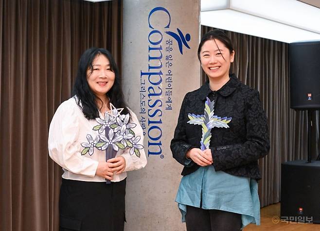 나난(왼쪽) 작가와 김예지 대표가 19일 서울 용산구 한국컴패션 사옥에서 꽃과 십자가 모양의 작품을 들고 밝게 웃고 있다. 신석현 포토그래퍼
