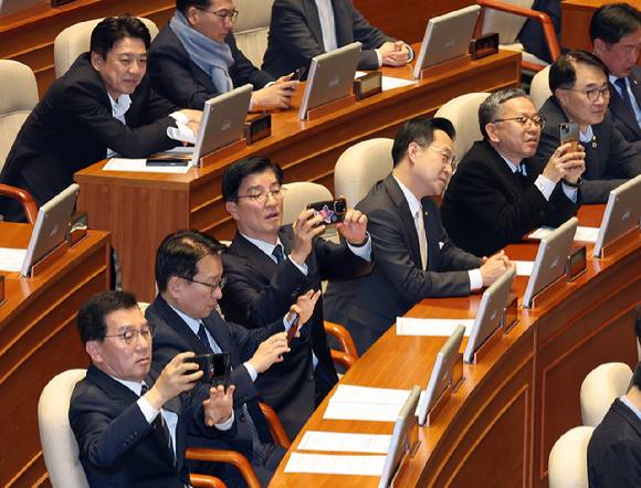더불어민주당 의원들이 20일 국회 본회의장에서 공소청법안(대안)이 통과되자 휴대폰을 꺼내 사진을 찍고 있다. 2026.3.20 [사진=연합뉴스]