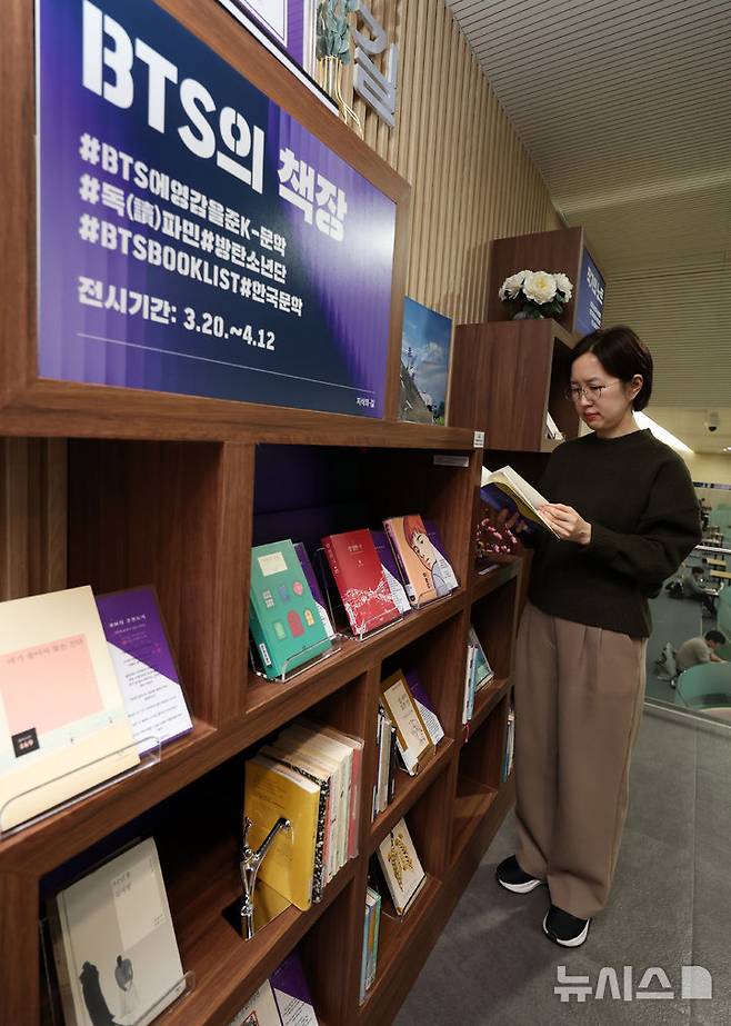 [서울=뉴시스] 이영환 기자 = 방탄소년단(BTS)이 완전체로 컴백하는 20일 오전 서울 서초구 국립중앙도서관 지식의 길에 마련된 BTS의 책장에서 한 시민이 BTS 멤버의 추천 도서를 살펴보고 있다. 방탄소년단은 이날 오후 1시 정규 5집 '아리랑'을 발매하며 국립중앙도서관 지식의 길에 마련된 BTS의 책장은 내달 12일까지 열린다. 전시 도서에는 한강의 '소년이 온다', 이민진의 '파친코', 손원평의 '아몬드', 김애란의 '비행운' 등의 소설이 배치된다. 또 윤동주의 '하늘과 별과 바람과 시' 초판본, 백석의 '사슴' 초판본, 나태주의 '꽃을 보듯 너를 본다' 등 시도 함께 전시된다. 2026.03.20. 20hwan@newsis.com