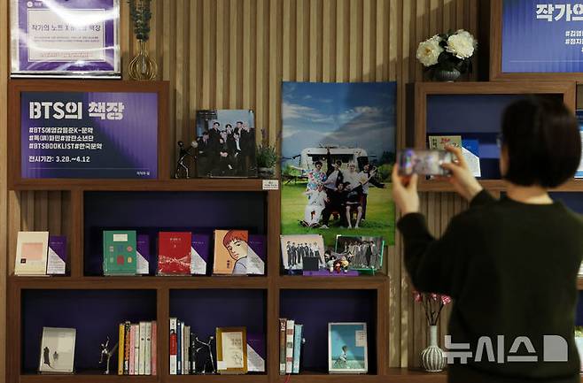 [서울=뉴시스] 이영환 기자 = 방탄소년단(BTS)이 완전체로 컴백하는 20일 오전 서울 서초구 국립중앙도서관 지식의 길에 마련된 BTS의 책장에서 한 시민이 BTS 멤버의 추천 도서를 휴대전화에 담고 있다. 방탄소년단은 이날 오후 1시 정규 5집 '아리랑'을 발매하며 국립중앙도서관 지식의 길에 마련된 BTS의 책장은 내달 12일까지 열린다. 전시 도서에는 한강의 '소년이 온다', 이민진의 '파친코', 손원평의 '아몬드', 김애란의 '비행운' 등의 소설이 배치된다. 또 윤동주의 '하늘과 별과 바람과 시' 초판본, 백석의 '사슴' 초판본, 나태주의 '꽃을 보듯 너를 본다' 등 시도 함께 전시된다. 2026.03.20. 20hwan@newsis.com