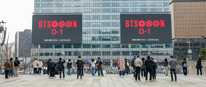 방탄소년단(BTS)의 서울 광화문광장 컴백 공연을 하루 앞둔 20일 서울 종로구 세종문화회관 계단에서 외국인 관광객들이 전광판에 송출되는 공연 광고를 기념촬영하고 있다.