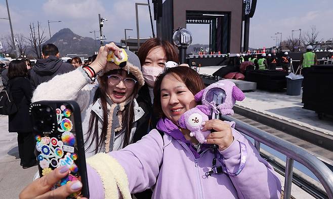 방탄소년단(BTS) 완전체 컴백 공연을 하루 앞둔 20일 서울 광화문광장 공연장 앞에 대만에서 온 아미(ARMY·팬덤명)들이 기념 사진을 찍고 있다. 뉴스1