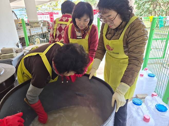 ‘우산고로쇠 수액 장 담그기’ 행사에서 슬로푸드 울릉군지부 회원들이 해발 400m 이상 고지대에서 채취한 고로쇠 수액을 활용해 장을 담그고 있다. 회원들 뒤편으로 채취한 고로쇠 수액이 담긴 말통들이 보인다. /슬로푸드 울릉군지부 제공
