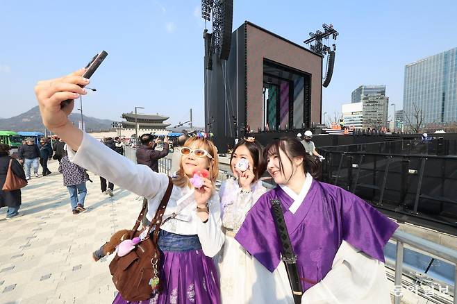 방탄소년단(BTS)의 컴백 공연을 하루 앞둔 20일 서울 종로구 광화문광장에서 태국에서 온 팬들이 BTS를 상징하는 보라색 한복을 입은 채 사전 설치된 무대를 배경으로 사진을 찍고 있다. 21일 오후 8시 광화문광장에서 시작되는 ‘BTS 컴백 라이브: 아리랑’은 넷플릭스로 세계 190여 개국에 생중계된다. 이한결 기자 always@donga.com