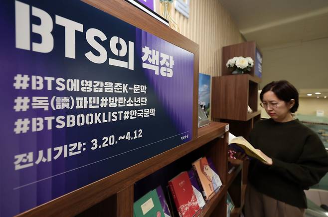 방탄소년단(BTS)이 완전체로 컴백하는 20일 오전 서울 서초구 국립중앙도서관 지식의 길에 마련된 BTS의 책장에서 한 시민이 BTS 멤버의 추천 도서를 살펴보고 있다. 뉴시스