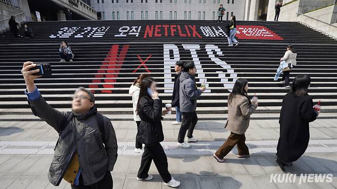 지난 16일 서울 종로구 세종문화회관에 부착된 방탄소년단(BTS)의 컴백 공연 홍보물 앞에서 한 시민이 기념사진을 촬영하고 있다. 남동균 기자