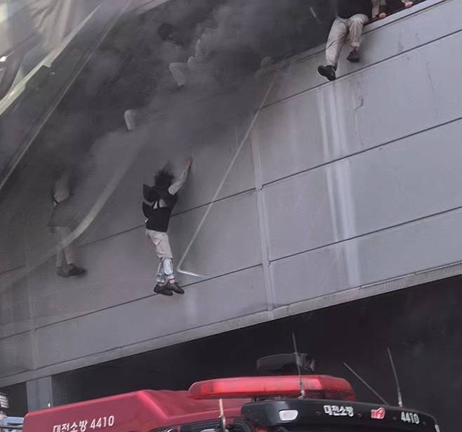 20일 오후 대전 대덕구 문평동 한 자동차부품 제조 공장에서 불이 나 검은 연기가 치솟는 가운데 직원들이 탈출을 위해 필사적으로 뛰어내리고 있다. 연합뉴스&nbsp;