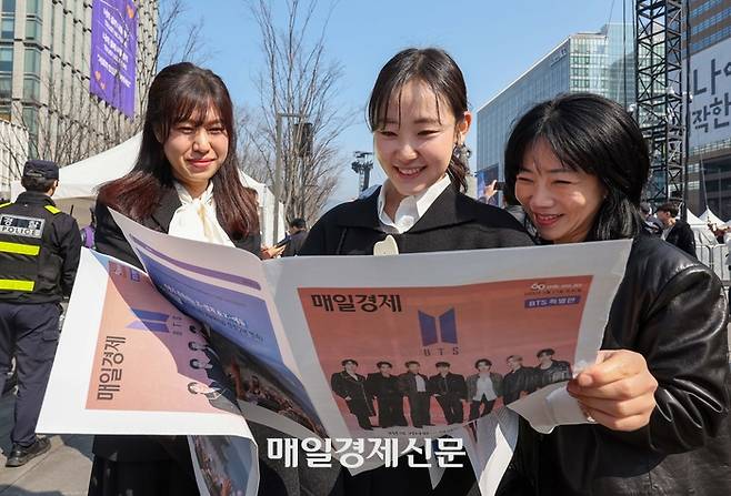 방탄소년단(BTS) 컴백 공연일인 21일 서울 광화문광장에서 외국인 관광객이 매일경제신문이 발행한 BTS 관련 특별판을 읽고 있다. 2026.3.21 [한주형기자]