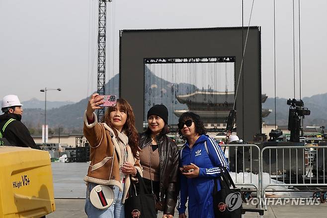 가시지 않는 여운 (서울=연합뉴스) 임화영 기자 = 방탄소년단(BTS) 공연 종료 다음 날인 22일 서울 종로구 광화문광장에서 BTS 팬들이 철수 중인 무대를 배경으로 기념촬영하고 있다. 2026.3.22 hwayoung7@yna.co.kr