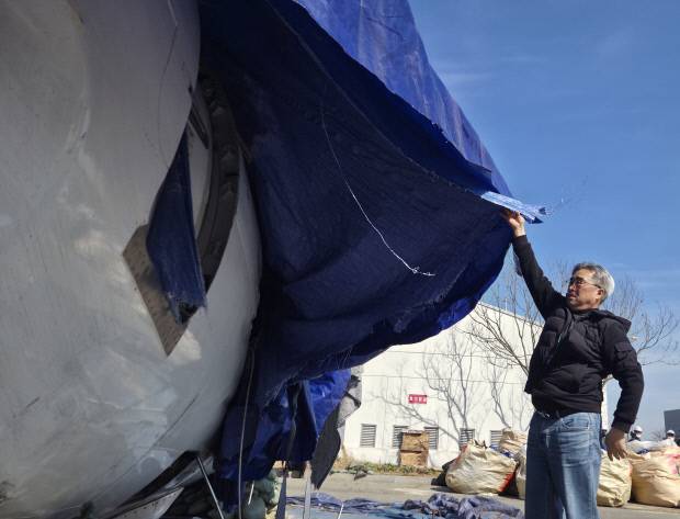 제주항공 참사 희생자 유가족이 무안국제공항 내 보안구역에 보관 중인 기체잔해를 살펴보고 있다.