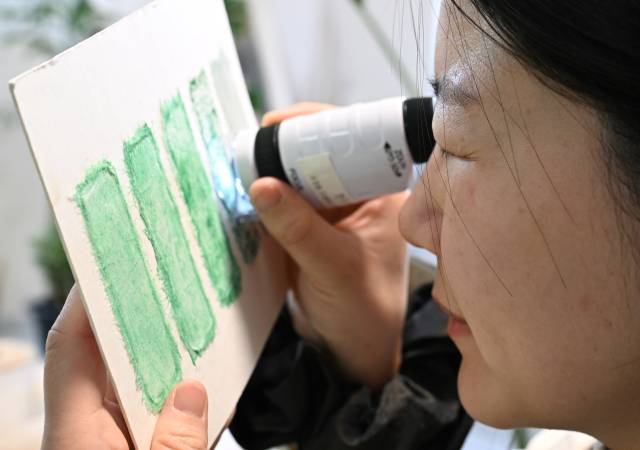 조현수 화가가 원하는 색을 찾기 위해 실험한 재료를 확대경으로 살펴보고 있다. /김승권 기자/