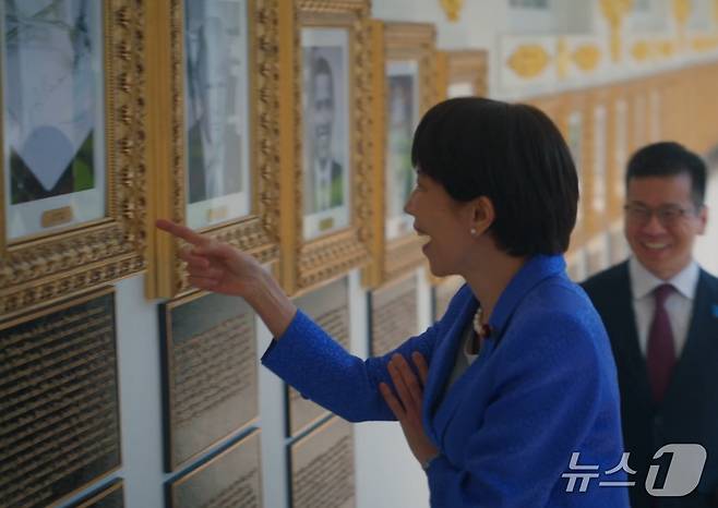 다카이치 사나에 일본 총리가 조 바이든 전 대통령의 초상화 자리에 그의 서명을 기계가 대신 그려주는 '오토펜' 사진이 걸려있는 것을 보고 웃음을 터뜨리고 있다. (백악관 X)