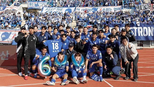수원 삼성 선수단이 지난 21일 김해FC를 3대0으로 꺾고 원정 응원단 앞에서 단체 사진을 찍고 있다. 공식전 통산 600승에 더해 창단 후 첫 개막 4연승을 달린 선수들은 최근 오른쪽 무릎 부상으로 수술을 앞둔 최지묵(18번)의 복귀를 기원하며 그의 유니폼을 들어올렸다. 오른쪽 맨 아래가 이정효 감독./한국프로축구연맹