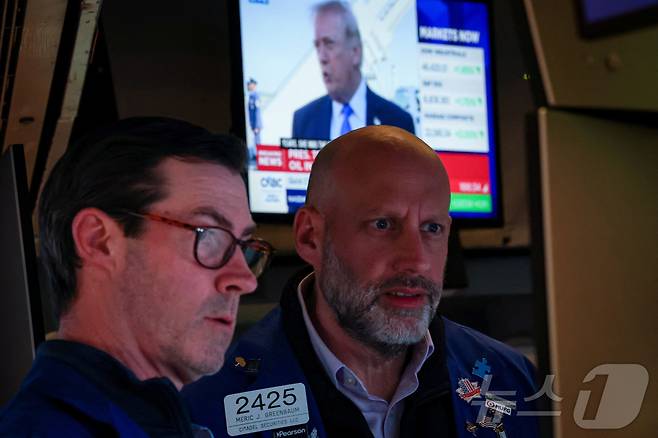 23일(현지시간) 도널드 트럼프 미국 대통령이 발언하는 뉴스 방송이 나오는 스크린을 뒤로 하고 뉴욕증권거래소(NYSE) 트레이더들이 근무하고 있다. 2026.3.23 ⓒ 로이터=뉴스1