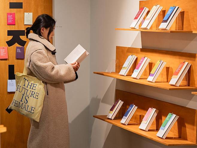 이달 중순 서울 영등포구 카페꼼마 여의도신영증권점에서 진행된 전시 ‘쓰는 독자, 읽는 비평가’에서 한 방문객이 블라인드북을 펼쳐 읽고 있다. 이 전시는 비평 속 문장을 통해 작품을 소개했다. 한국문화예술위원회 제공