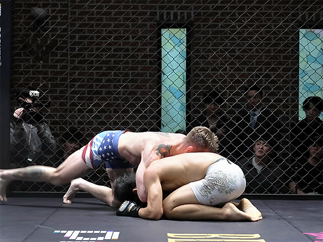 미국팀 레이크 지가 2026년 3월 경기도 오산시 종합격투기 국가대항전 ‘블랙컵’ 준준결승 밴텀급 경기에서 대한민국 알파 ‘리바이’ 김유찬을 넘어뜨린 후 무릎으로 차고 있다. 블랙컵 첫 시즌은 유튜브 채널 ‘블랙컴뱃’ 유료 멤버십 단독 생중계다. 사진=이데아 파라곤