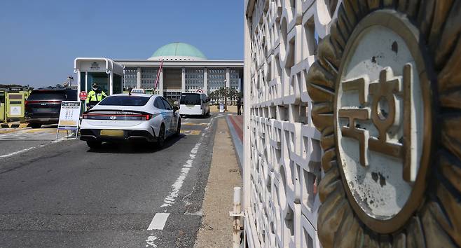 공공기관 차량 5부제 시행 첫날인 25일 서울 여의도 국회 정문에서 경찰이 운전자에게 우회로를 안내하고 있다. [연합]