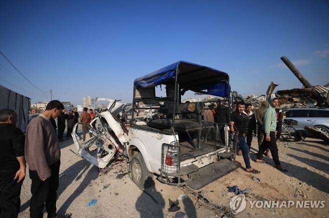 15일(현지시간) 가자지구에서 이스라엘의 공습을 받은 경찰차를 팔레스타인인들이 살펴보고 있다. AFP 연합뉴스