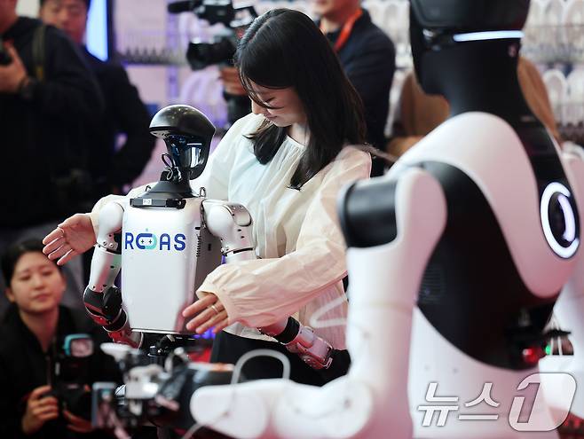 4일 서울 강남구 코엑스에서 열린 ‘2026 스마트공장·자동화산업전(AW 2026)’에서 참관객이 중국 휴머노이드 로봇 유니트리의 G1과 인사를 나누고 있다. 2026.3.4 ⓒ 뉴스1 박지혜 기자