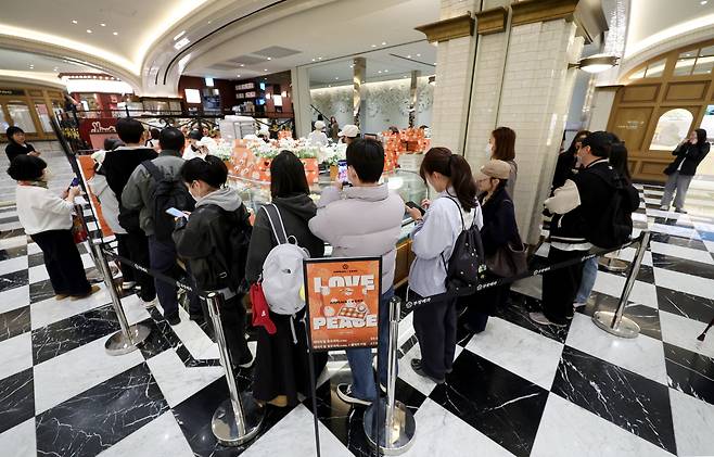 가수 지드래곤(G-DRAGON)이 설립한 저스피스 재단과 80년 전통의 부창제과가 협업한 '데이지 밤(DAISY BOMB) 호두과자'가 정식 출시된 26일 서울 신세계 백화점 강남점 '스위트파크' 팝업스토어 부창제과에서 팬들이 제품을 구매하기 위해 줄을 서고 있다. /뉴시스