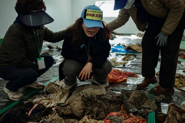 김유진 유가족협의회 대표가 3월 19일 분류를 마친 수천 점의 유류품 가운데서 동생의 옷가지를 발견하고서 오열하고 있다. 무안=하상윤 기자