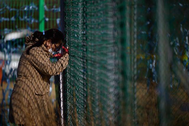 3월 19일 유족 오정순(56)씨가 유해 추정 물체 수습이 이뤄지고 있는 무안국제공항 활주로 담장 밖에서 철조망을 부여잡은 채 고개를 떨구고 있다. 무안=하상윤 기자