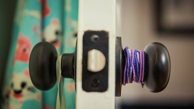 넷플릭스 다큐멘터리 <텅 빈 모든 방>이 찾은 샬롯 베이컨의 방. 문고리에 보라색 머리끈이 겹겹이 걸려있다. 6살이던 베이컨은 2012년 12월14일 미국 코네티컷주 샌디 훅 초등학교 총격 사건으로 사망했다. 넷플릭스 제공