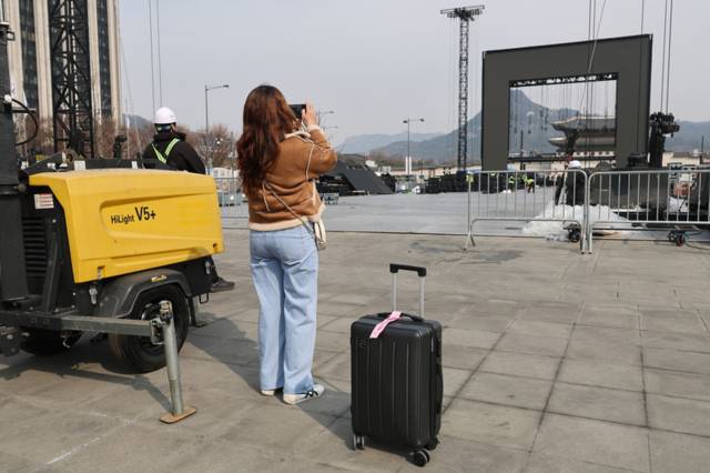 ▲ 방탄소년단(BTS) 공연 종료 다음 날인 22일 서울 종로구 광화문광장에서 BTS 팬이 철수 중인 무대를 기념촬영하고 있다. 연합뉴스