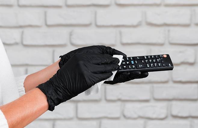 리모컨을 소독용 티슈로 닦는 모습. 여러 사람이 함께 사용하는 물건은 정기적인 관리가 필요하다. 사진=클립아트코리아