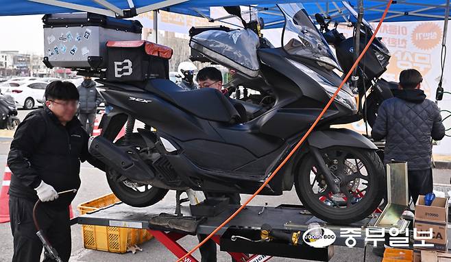 30일 오전 수원시 장안구 수원종합운동장 주차장에서 열린 '이륜차 사고 예방과 친환경 운행을 위한 무상 안전 점검 및 소모품 교체 행사'에서 관계자들이 오토바이를 점검하고 있다. 김경민기자