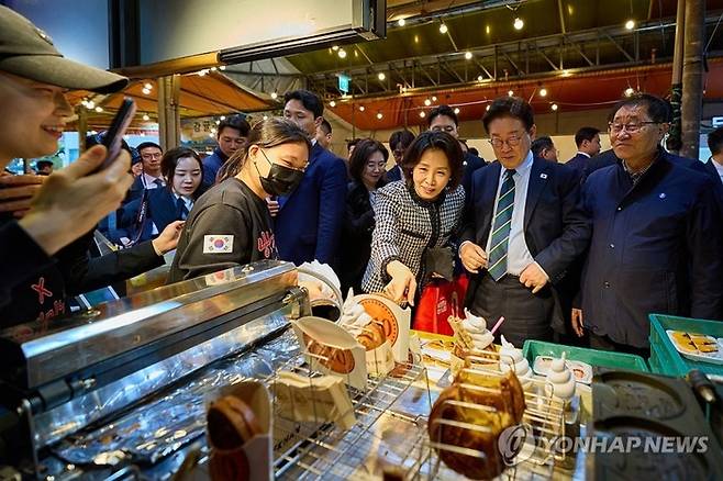 이재명 대통령이 30일 제주 타운홀미팅을 마친 뒤 김혜경 여사와 함께 제주시 동문시장을 찾아 간식을 구매하고 있다. 2026.3.30 [청와대 제공]