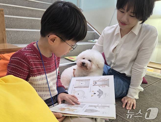 한국인간동물상호작용연구회(카이)가 서울 광진구립아차산숲속도서관에서 진행한 동물매개 읽기 프로그램에서 김시현 어린이(왼쪽)가 리딩독 '홀릭이'에게 책을 읽어주고 있다. ⓒ 뉴스1 한송아 기자