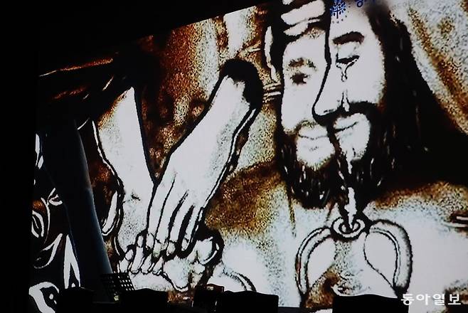 예수 그리스도가 제자들의 발을 씻어주는 모래예술이 영상을 통해 나오고 있다. 김재명 기자 base@donga.com