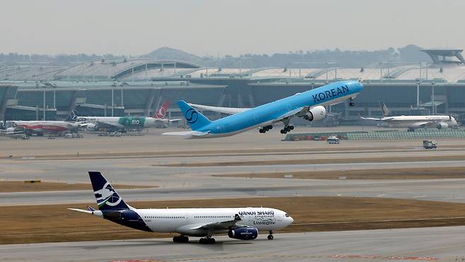 지난달 30일 인천국제공항 계류장에 대기하는 항공기 앞으로 대한항공 항공기가 이륙하고 있다. /뉴스1