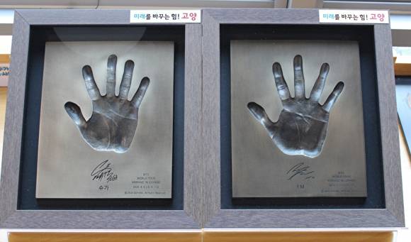 고양관광정보센터에서 개최하는 특별전에서 방탄소년단(BTS) 멤버들의 생생한 손도장과 친필 사인이 새겨진 동판 핸드프린팅을 나란히 전시하고 있다. [사진=고양시]