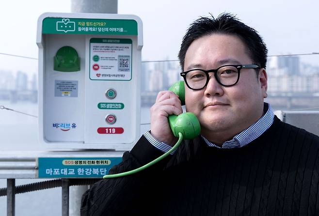 SOS생명의전화를 주도한 박성민씨가 지난달 27일 서울 마포대교 위에서 전화기를 귀에 대고 있다. 2011년 전화가 설치된 마포대교만 수십번 방문했다고 한다. 장진영 기자