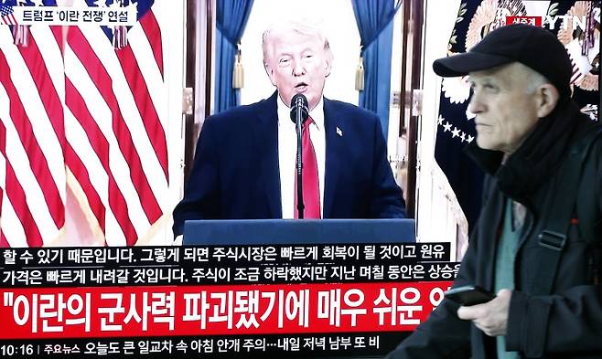 2일 오전 서울시 용산구 서울역 대합실에서 한 외국인 관광객이 도널드 트럼프 미국 대통령의 이란 전쟁 상황 관련 대국민 연설 TV 생중계 앞을 지나고 있다. 뉴스1 제공