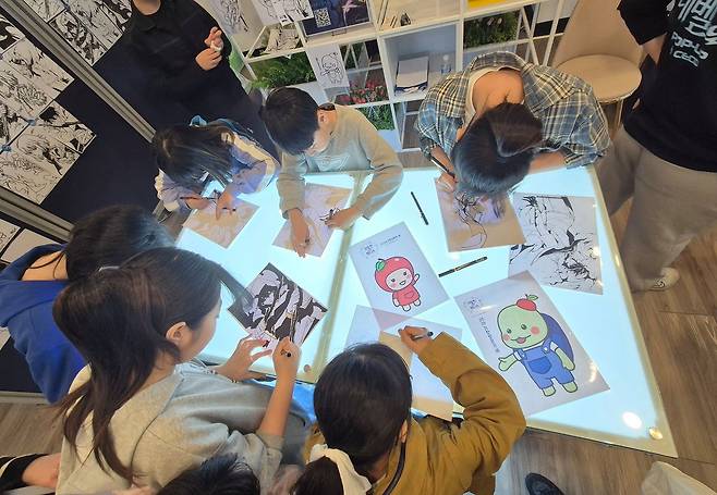 지난달 29일 경남 창원컨벤션센터(CECO)에서 진행 중인 '나 혼자만 레벨업 팝업 스토어'에 참여한 어린 관람객들이 웹툰 그림을 따라 그리고 있다. 안대훈 기자