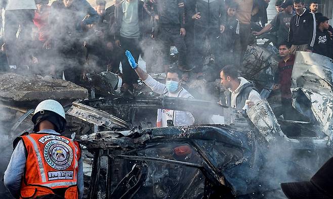 4일(현지시간) 가자지구 중부 자와이다 마을 인근에서 이스라엘의 공습에 피격당한 차량이 불에 탄 가운데, 구조대원들이 희생자를 수색하고 있다. AP연합뉴스