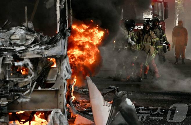 18일(현지시간) 브라질 리우데자네이루 중심부에서 경찰 작전 중 마약 밀매업자들이 방화한 것으로 추정되는 버스의 불을 끄기 위해 소방관들이 가정용 소화기를 사용하며 사투를 벌이고 있다. 2026.03.18.ⓒ AFP=뉴스1