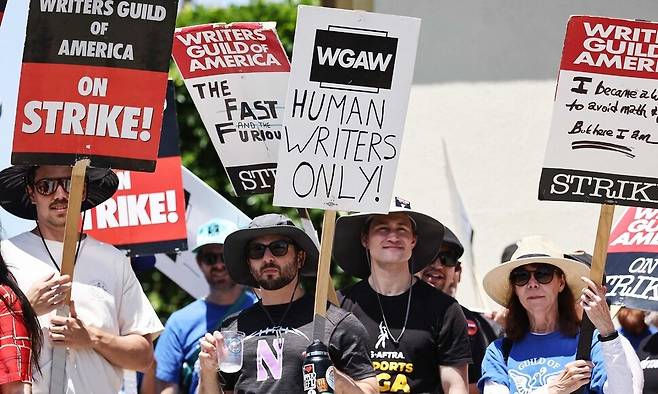2023년 7월12일 미국 로스앤젤레스 파라마운트 스튜디오 앞에서 파업 중인 미국작가조합(WGA) 소속 작가들이 손팻말 시위를 벌이고 있다. 팻말에는 “오직 인간 작가만!”이라고 적혀 있다. 로스앤젤레스/AFP 연합뉴스