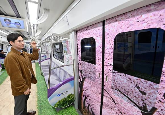 지하철 5호선(하남선) 전동차에 탑승한 시민들이 미사한강모랫길과 하남벚꽃길 등 하남의 명소로 꾸며진 ‘하남 풍경열차’ 내부를 살펴보고 있다. [사진=하남시]