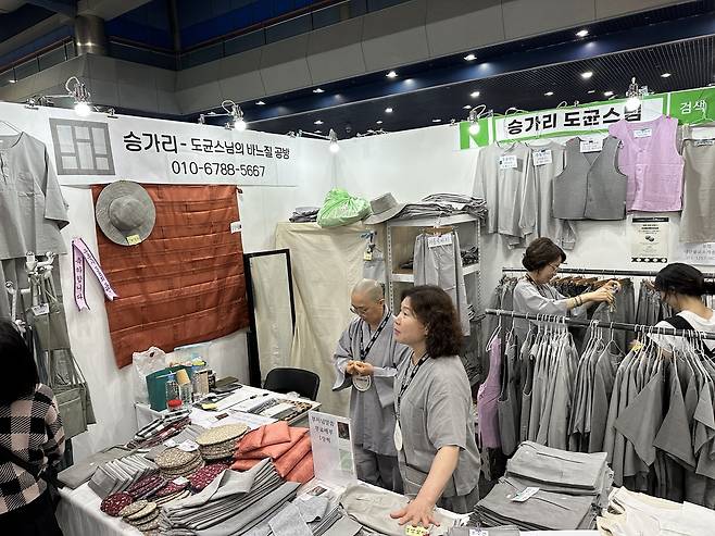 Ven. Dogyun of Hyegwangsa (left, background) stands at her booth showcasing handmade monastic items at the 2026 Seoul International Buddhism Expo. (Tammy Park/The Korea Herald)